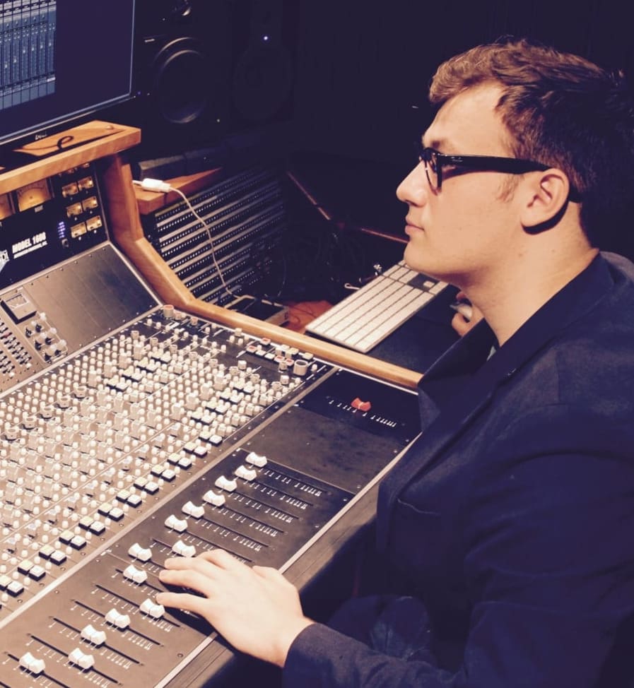 A man is sat in a music studio.